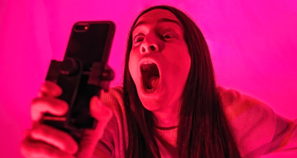 Image of woman screaming into a smartphone.